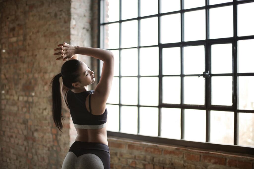 Woman in Black Sports Bra While Standing Near Window